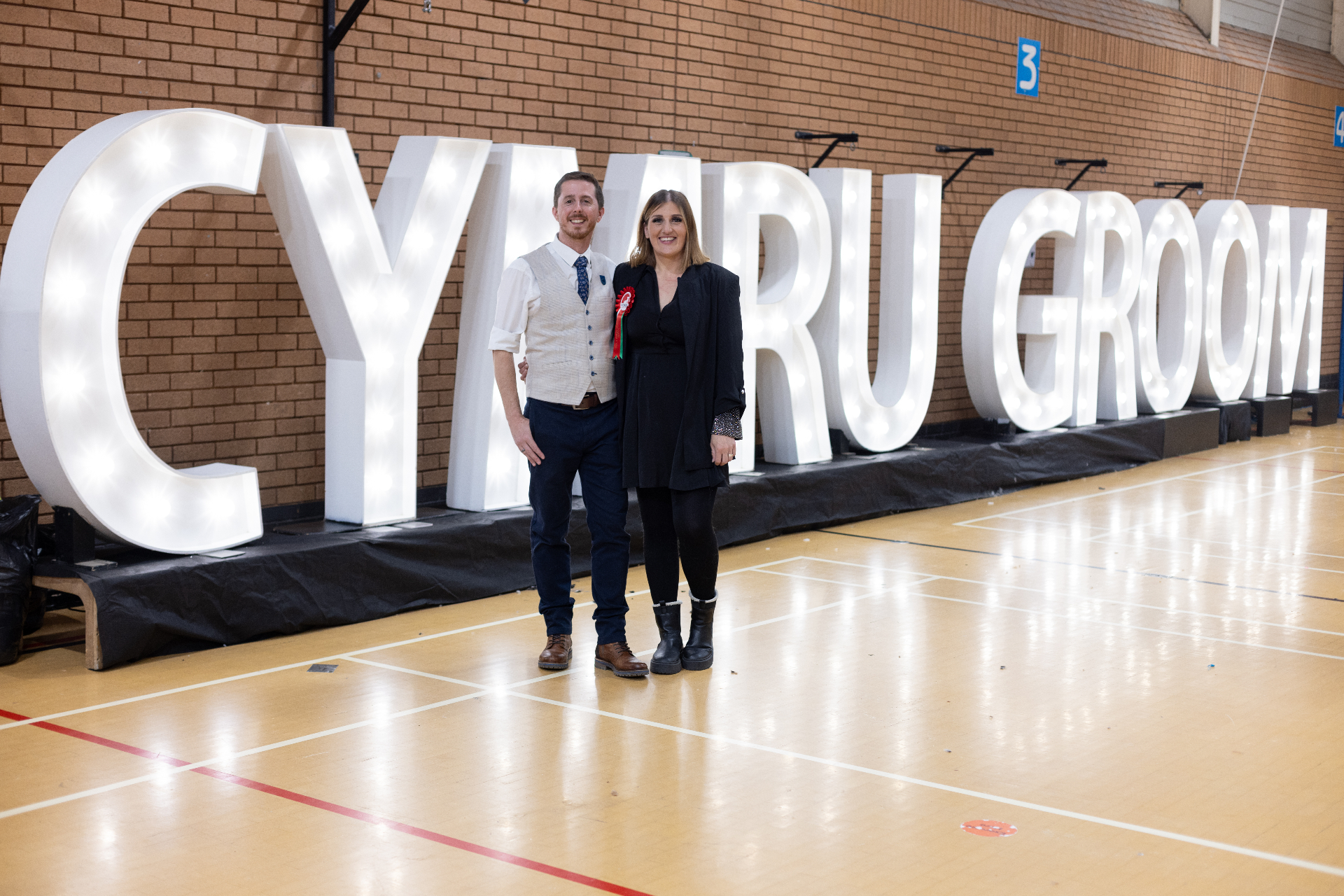 Cymru Groom founders in front of illuminated event letters